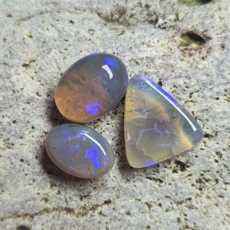 Three opal stones on a textured stone surface