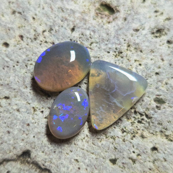 Three opal stones on a textured stone surface