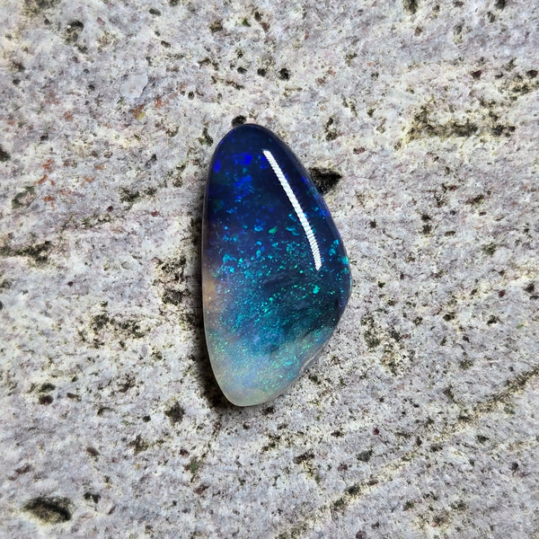 Blue and green gemstone on a textured gray surface