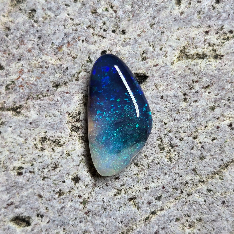 Blue and green gemstone on a textured gray surface