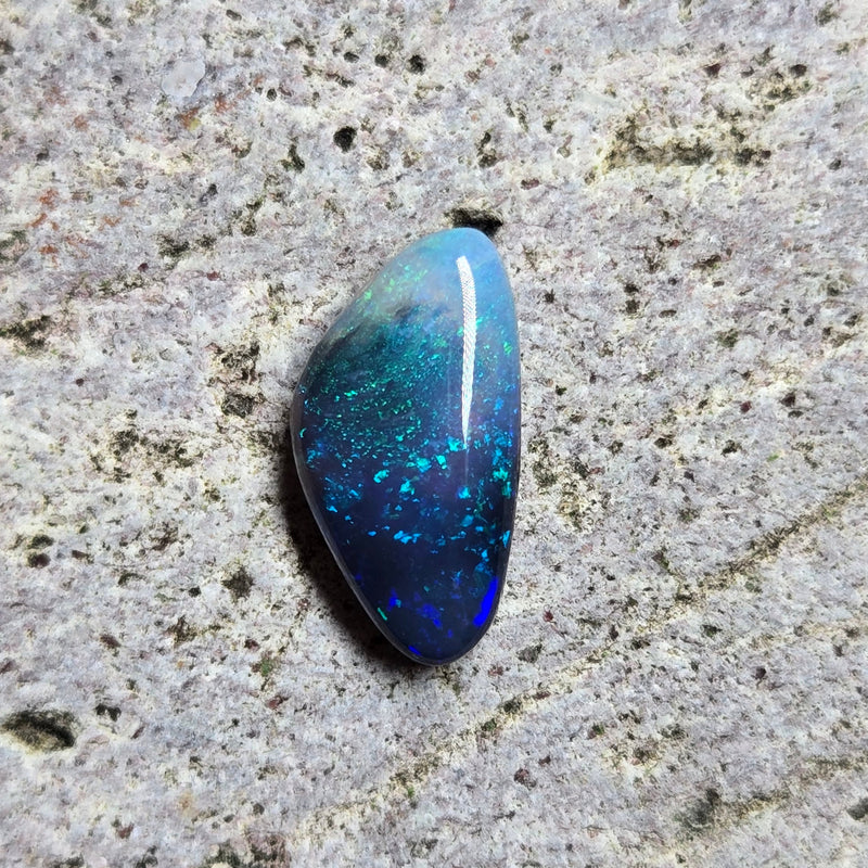 Blue opal stone on a textured gray surface