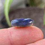 Blue stone held between fingers with a blurred background