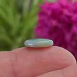 Opal stone on profile on finger on blurred background