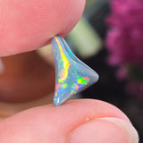 Opal stone held between fingers with a blurred background