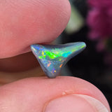 Opal stone held between two fingers with a blurred background
