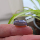 Purple stone held between fingers with a blurred indoor background