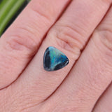 Opal stone held between fingers against a blurred background