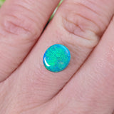 Opal stone held between fingers against a blurred natural background