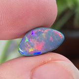 Opal stone held between fingers with a blurred natural background