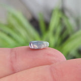opal on the finger with blurred plant background
