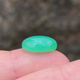 Green stone held between fingers against a blurred background