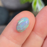 Opal stone held between fingers with a blurred background