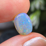 Opal stone held between fingers with a blurred natural background