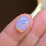 Close-up of a hand with a glowing blue and purple gemstone on a blurred background