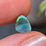 Opal stone held between two fingers with a blurred background