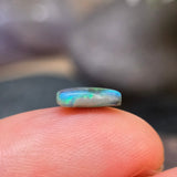 Opal stone held between fingers with a blurred background