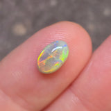Opal stone held between fingers against a blurred background