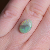 Opal stone held between fingers on a light skin background