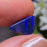 Blue stone held between fingers with a blurred natural background