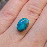 Opal stone held between fingers on a light skin background