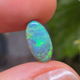 Opal stone held between fingers with a blurred natural background