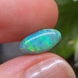 Opal stone held between fingers with a blurred natural background
