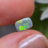 Opal stone held between fingers with a blurred natural background