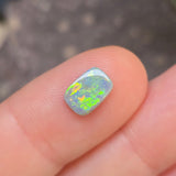 Opal stone held between fingers against a blurred background