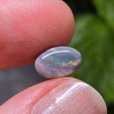Opal stone held between two fingers with a blurred green background