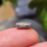 Small gemstone held between fingers with a blurred background