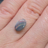 Opal stone held between fingers against a skin background